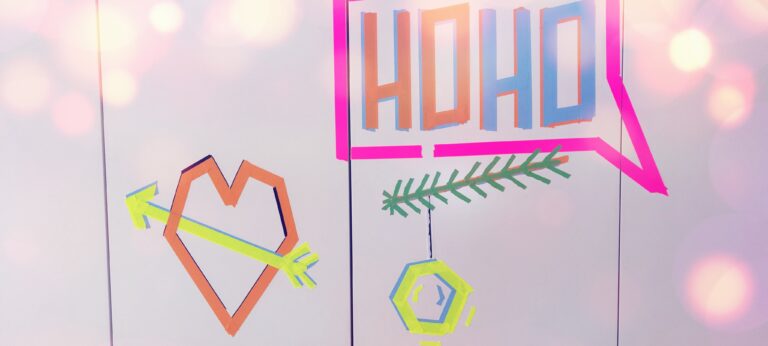 An einer weißen Wand sind verschiedene weihnachtliche Elemente mit farbigem Walltape angebracht