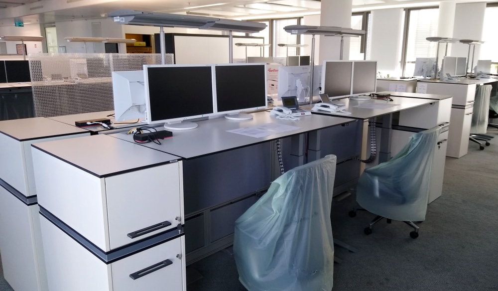 In einem Open Space Büro ist der Umzug abgeschlossen, alle Arbeitsplätze sind bereit zum Wiedereinzug, die Stühle sind mit Kunststoffhüllen geschützt