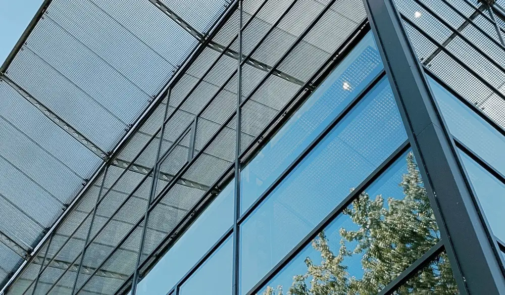 Ausschnitt einer Bürofassade mit breiten Fenstern und äußerem Blendschutz